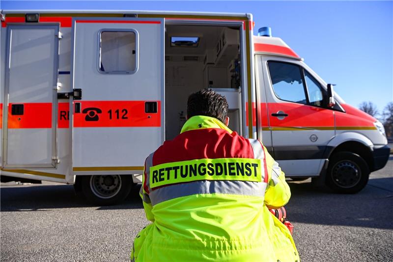 «Rettungsdienst» steht auf der Jacke eines Mannes vor einem Rettungswagen der Feuerwehr.