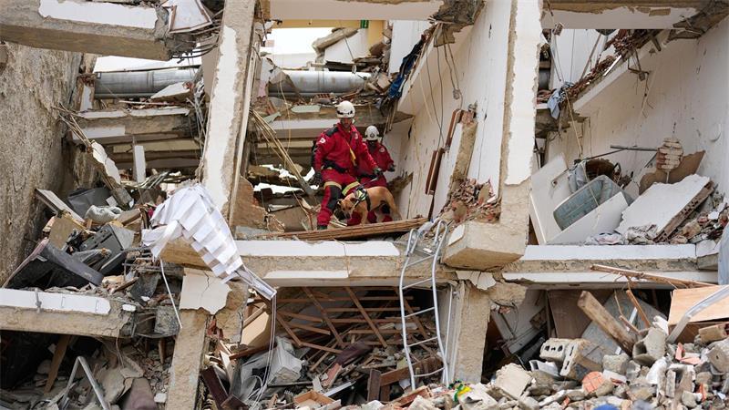 Rettungskräfte aus Spanien durchsuchen die Trümmer eines Gebäudes.