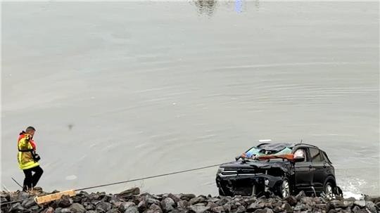 Rettungskräfte befreiten eine Person aus dem im Wasser versinkenden Fahrzeug.
