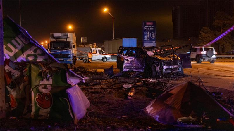Rettungskräfte räumen in Kiew Trümmer und beschädigte Straßeninfrastruktur in der Nähe eines zerstörten Autos nach einem nächtlichen russischen Angriff weg.