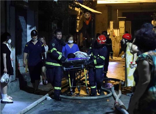 Rettungskräfte tragen eine Person aus einem brennenden Gebäude.