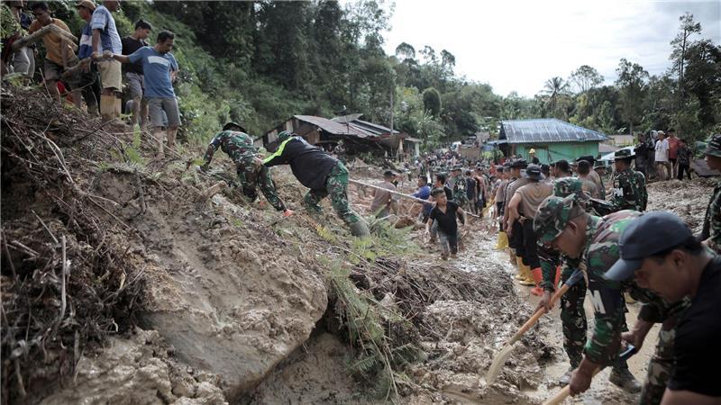 Rettungskräfte und Dorfbewohner beseitigen Schlamm.
