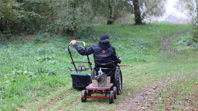 Rollo bei der Arbeit: Mit seinem am Rollstuhl befestigten Rasenmäher umrundet er die Grünanlage.