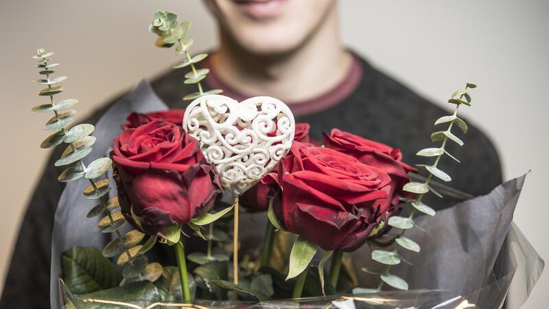 Valentinstag: Was Sie beim Blumenkauf beachten müssen Ein Mann hält einen Strauß Rosen