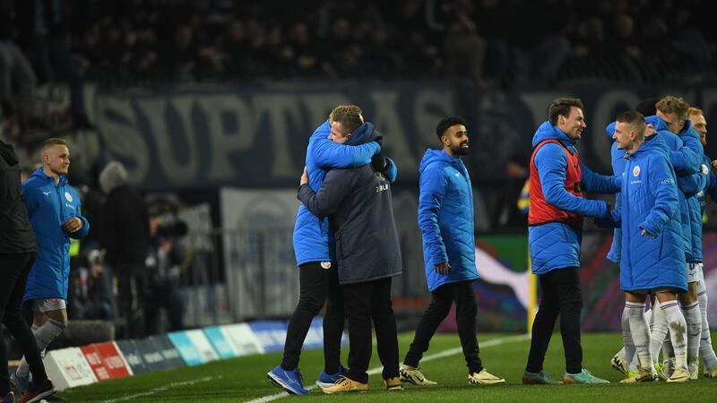 Rostock-Trainer erleichtert: „Du darfst dich nicht aufgeben“ Rostocks Trainer Mersad Selimbegovic (2.v.l) jubelt nach dem Schlusspfiff.
