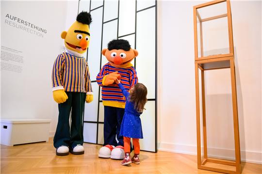 Roxy zeigt den Figuren Ernie und Bert ihr Elmo-Kuscheltier. Zum 50. Jubiläum der Sesamstraße veranstaltet das Museum für Kunst und Gewerbe einen Aktionstag für die ganze Familie. Foto: Jonas Walzberg/dpa