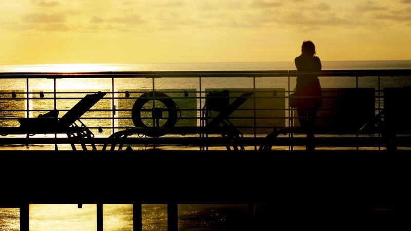 Norovirus: Wie hoch ist das Risiko auf Kreuzfahrtschiffen? Eine Frau steht an der Reling einer Kreuzfahrtschiffs
