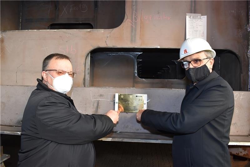 Russlands Generalkonsul Andrei Sharashkin (links) und Staatsrat Andreas Rieckhof schrauben die Plakette an.