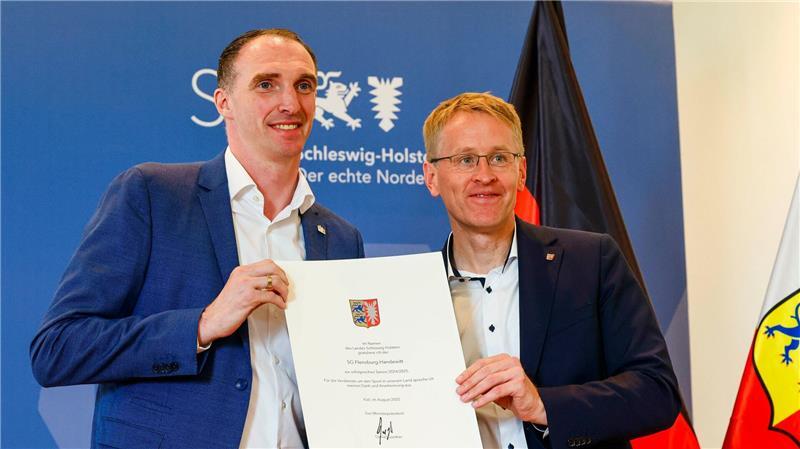 Wem Handball-Fan Günther die Daumen drückt SG-Geschäftsführer Holger Glandorf (l) mit der Urkunde, die ihm von Ministerpräsident Daniel Günther überreicht wurde.