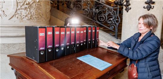 Sabine Mertens, Sprecherin der Volksinitiative „Schluss mit Gendersprache in Verwaltung und Bildung“, legt die Ordner mit 16.457 Unterschriften zur Übergabe an den Senat im Rathaus ab. Foto: Markus Scholz/dpa