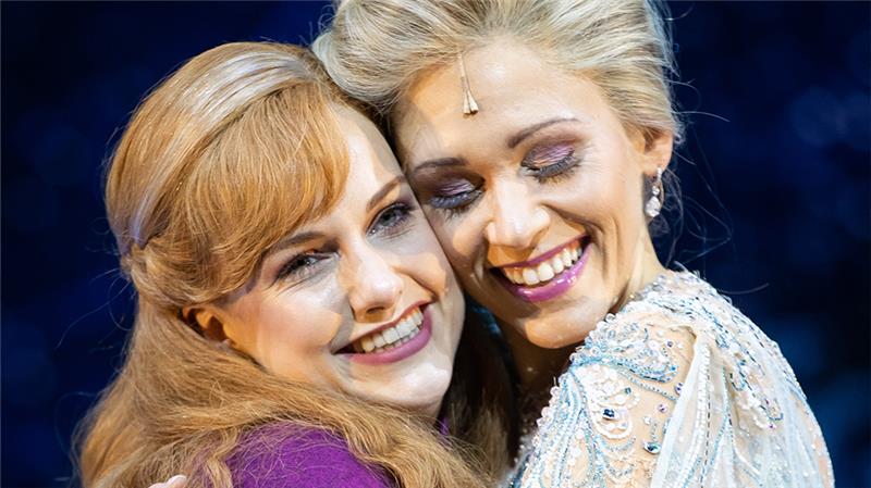 Sabrina Weckerlin (Eiskönigin Elsa, r) und Celena Pieper (ihre Schwester Anna), Musicaldarstellerinnen in dem neuen Musical "Die Eiskönigin", stehen bei einer gestellten Fotoszene nach einer Presse-Probe auf der Bühne im Stage Theater an der Elbe. Foto: Christian Charisius/dpa