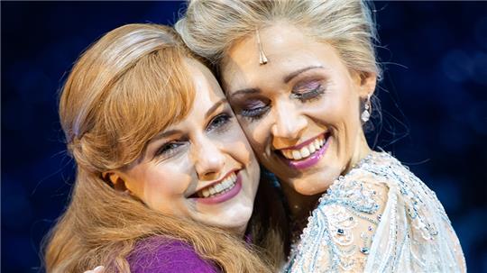 Sabrina Weckerlin (Eiskönigin Elsa, r) und Celena Pieper (ihre Schwester Anna), Musicaldarstellerinnen in dem neuen Musical "Die Eiskönigin", stehen bei einer gestellten Fotoszene nach einer Presse-Probe auf der Bühne im Stage Theater an der Elbe. Foto: Christian Charisius/dpa