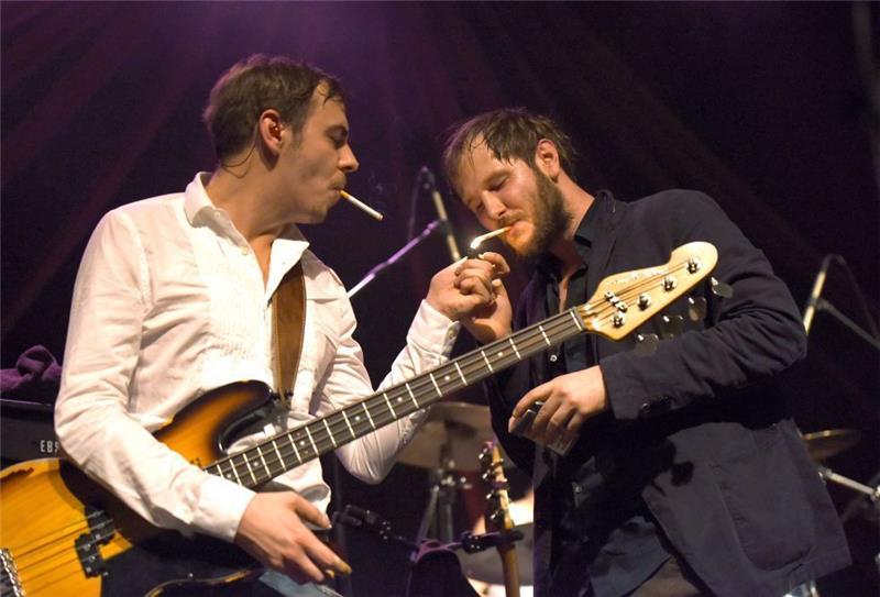 Sänger Michael Marco Fitzthum und Bassist Reinhold Weber von der österreichischen Band Wanda zünden sich bei einem Konzert in Dortmund Zigaretten an. Foto Caroline Seidel/dpa