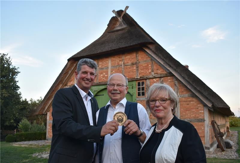 Samtgemeinde-Bürgermeister Matthias Herwede und Rainer Kröger halten den „Ehrentaler“ in ihren Hände. Der Vorsitzende des Vereins Bäuer liches Hauswesen Bliedersdorf ist am Donnerstagabend für seine Verdienste geehrt worden. Mit ihm freut s