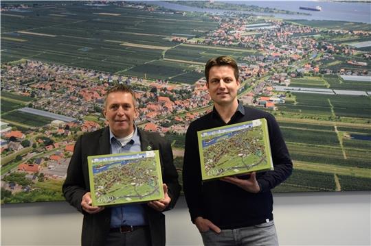 Samtgemeinde-Bürgermeister Timo Gerke und Mark Schober vom Wimmelwerk präsentieren das neue Puzzle. Foto: Battmer