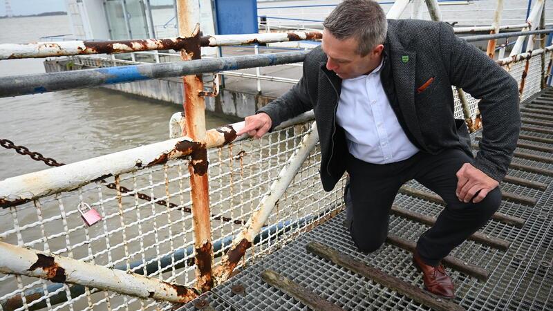 Samtgemeinde-Bürgermeister Timo Gerke zeigt auf eine der Roststellen an der Landungsbrücke.
