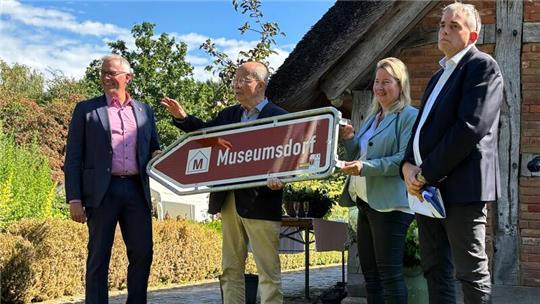 Samtgemeindebürgermeister Knut Willenbockel (links), stellvertretende Landrätin Birgit Butter und Bürgermeister Tobias Terne (beide rechts) schenken Vereinsvorstand Rainer Kröger (mittig) einen symbolischen Wegweiser.