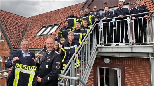 Samtgemeindebürgermeister Matthias Hartlef (links), Gemeindebrandmeister Sven Dammann (rechts) sowie Mitwirkende der AED-Gruppe und der Feuerwehr mit Ersthelferjacken.