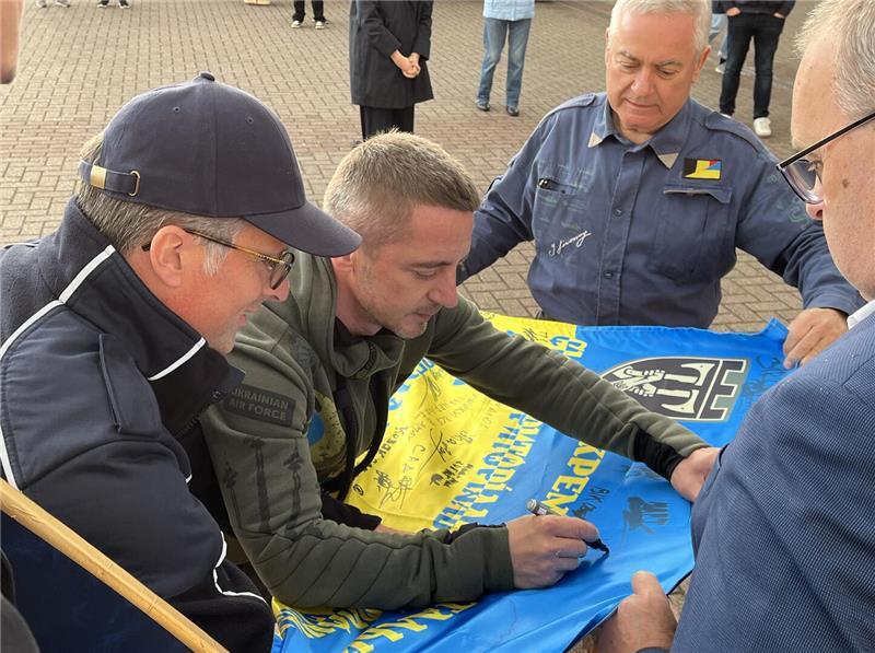 Sascha Kaflowsky übergab eine Flagge seiner Drohnen-Brigade mit Unterschriften seiner Kameraden an Landrat Kai Seefried (links), hinten ist Grischa Kaflowsky zu sehen.