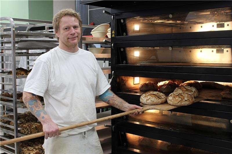 Sascha Schäfer in der gläsernen Backstube der „ Backsau “. Gerade holt er das Hausbrot aus dem Ofen. Foto: Frank