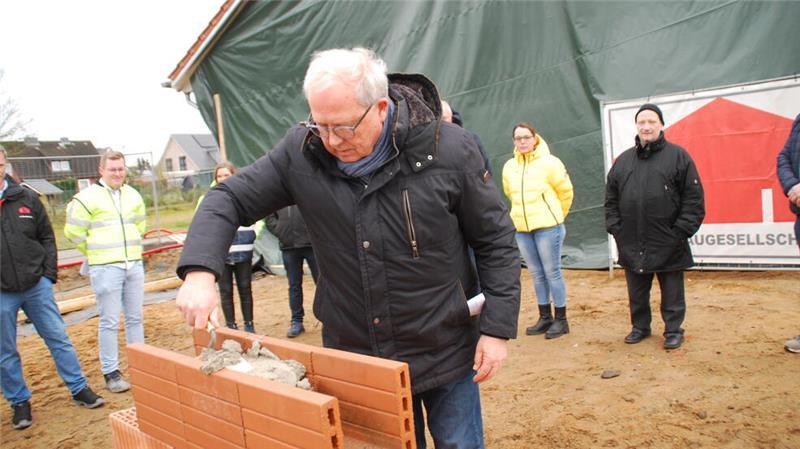 Sauensieks Bürgermeister Rolf Suhr mauert bei der Grundsteinlegung die Zeitkapsel ein.