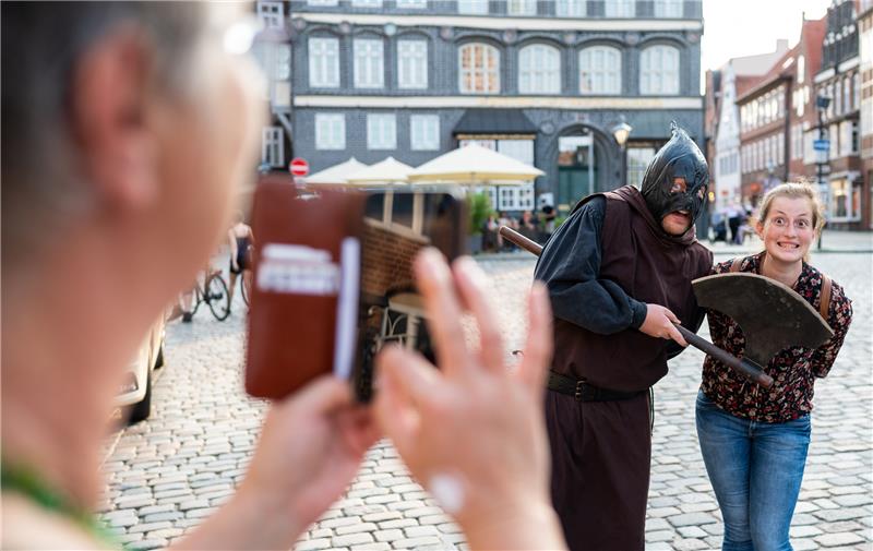 Ein Mordsspaß: Lüneburger Henkerführung mit schwarzem Humor Scharfrichter Meister Hans (Mitte) alias Leif Scheele lässt sich zusammen mit Olivia Katzwedel (rechts) während der Stadtführung fotografieren. Foto: Philipp Schulze/dpa