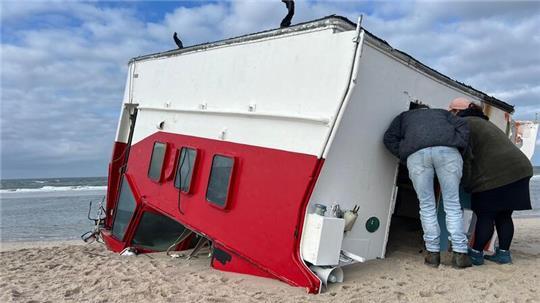 Schaulustige schauen sich auf Sylt einen angespülten Bootsaufbau an.
