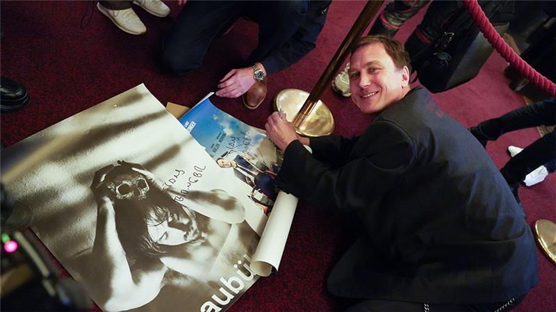 Schauspieler Lars Eidinger schreibt nach dem Fotocall des Films "Lars Eidinger - Sein oder nicht sein" im Rahmen des 30. Filmfests Hamburg im Passage Kino auf dem Boden knieend Autogramme für die wartenden Fans. Foto: Marcus Brandt/dpa
