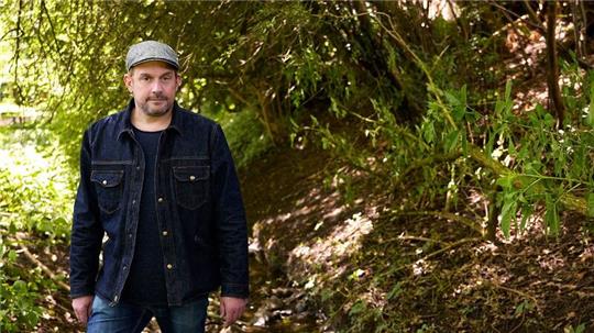Schauspieler Sebastian Bezzel an einem Bach.