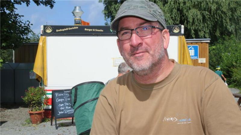 Schere statt Schirm: Camper Stefan Mank aus dem Ruhrgebiet pflegt seinen Stellplatz - auch bei feuchtem Untergrund.