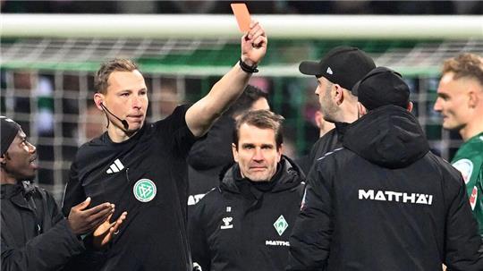 Schiedsrichter Martin Petersen (2.v.l) zeigt Werder Trainer Ole Werner (3.v.r) nach dem Abpfiff die Rote Karte auf dem Platz.