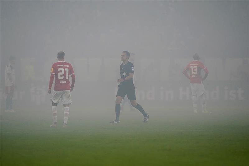 Pyro-Ärger und verschossener Elfmeter: HSV mit erstem Remis der Saison Schiedsrichter Robert Hartmann (M) unterbricht das Spiel wegen zuviel Rauch, nachdem Kaiserslautern-Fans Feuerwerkskörper auf der Tribüne abgebrannt haben. Foto: Marcus Brandt/dpaBildtext