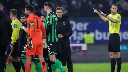 Schiedsrichter Sören Storks (r) schickt die Spieler beider Mannschaften nach Protesten von Hannovers Fans in die Kabinen.