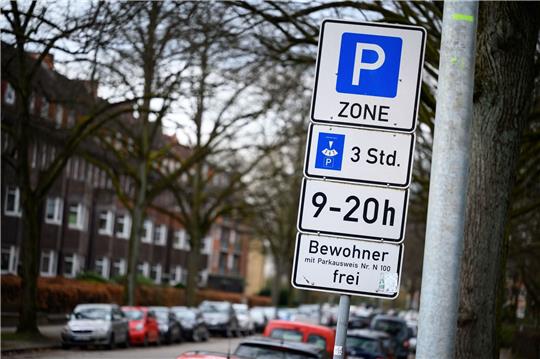 Schilder mit Hinweisen zu einer Bewohnerparkzone stehen an einer Wohnstraße.