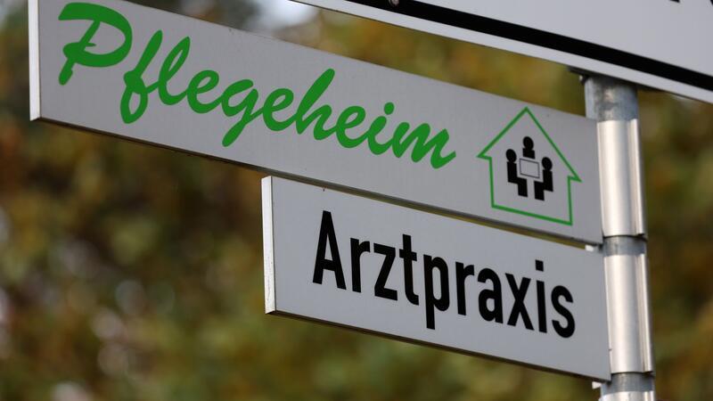 Schilder weisen den Weg zu einer Arztpraxis und zu einem Pflegeheim.