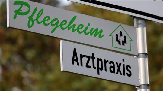 Schilder weisen den Weg zu einer Arztpraxis und zu einem Pflegeheim.