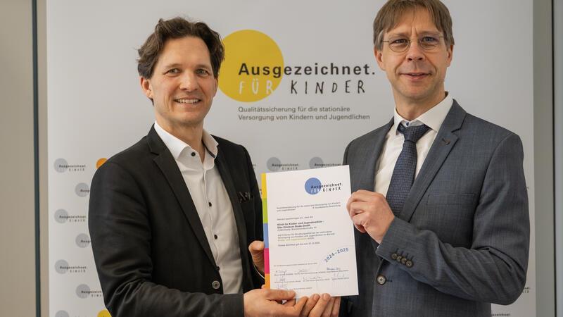 Siegel für Elbe Kliniken: Kinder- und Jugendklinik ist ausgezeichnet Schleswig-Holsteins Gesundheitsstaatssekretär Oliver Grundei (links) überreicht Chefarzt Dr. Markus Krüger das Zertifikat. Foto: Kommission Ausgezeichnet. Für Kinder.