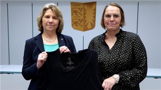 Schleswig-Holsteins Justizministerin Kerstin von der Decken (links, CDU) und die Gerichtsvollzieherin Mareile Dufke zeigen eine Schutzweste für Gerichtsvollzieher. 