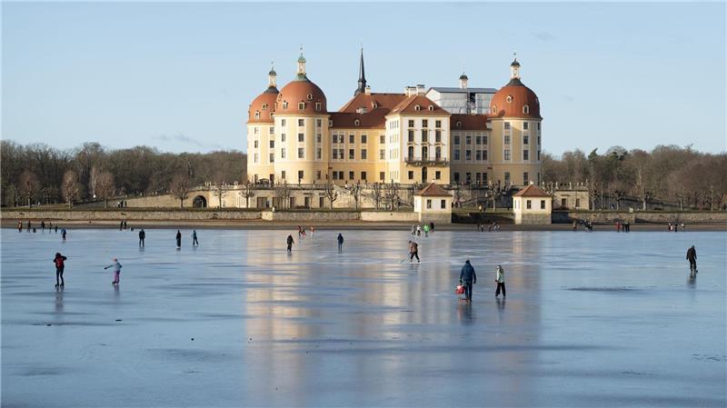 Schlittschuhläufer sind auf dem Eis vor Schloss Moritzburg in Sachsen unterwegs.