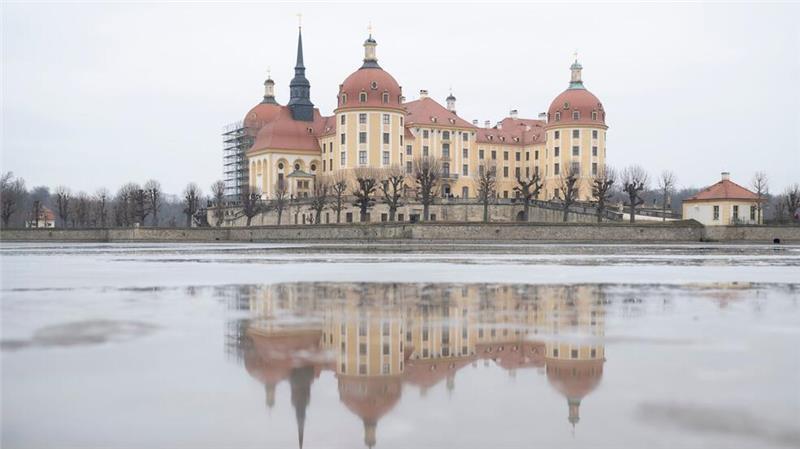 Schloss gespiegelt: Das Schloss Moritzburg in Sachsen spiegelt sich im Tauwassser auf in einer Eisfläche auf dem Schlossteich.