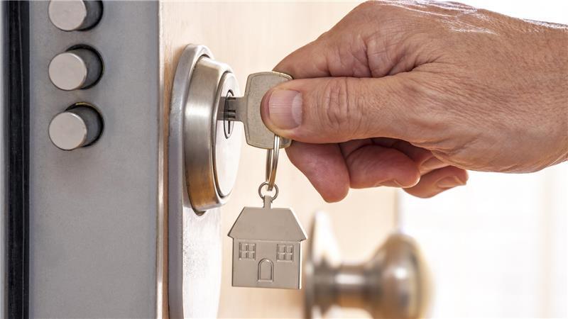 Ein fasst einen Schlüssel an, der in einem Schloss steckt.