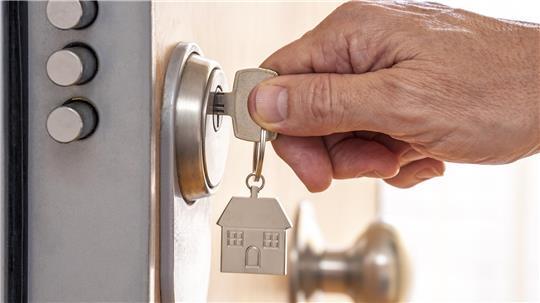 Ein fasst einen Schlüssel an, der in einem Schloss steckt.