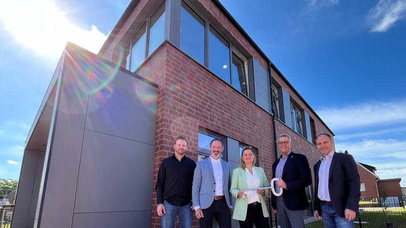 Schlüsselübergabe: Christoph Lührs und Niels Schütte vom Bauunternehmen Lindemann nehmen die kommissarische Schulleiterin Daniela Rambow und Bürgermeister Knut Willenbockel gemeinsam mit ihrem Kollegen Jörg Müller vor dem aufgestockten Schulbau der Oberschule Horneburg in die Mitte (von links).