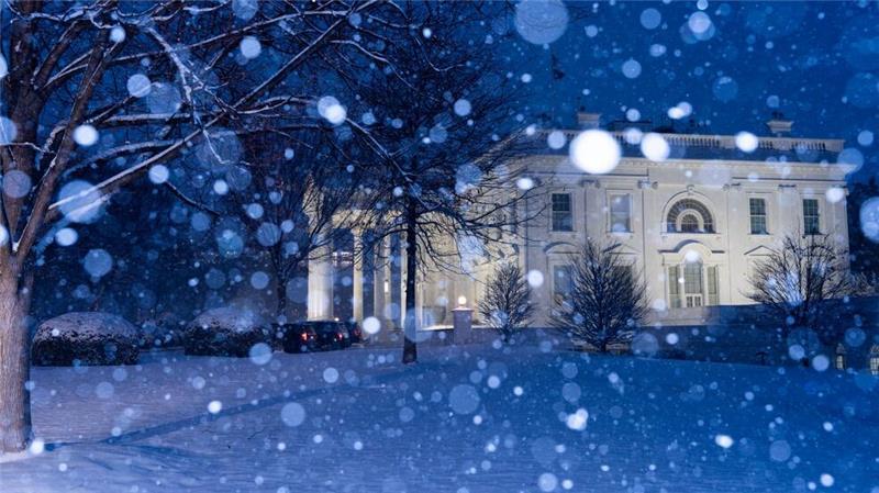 Schnee fällt auf das beleuchtete Weiße Haus in Washington.