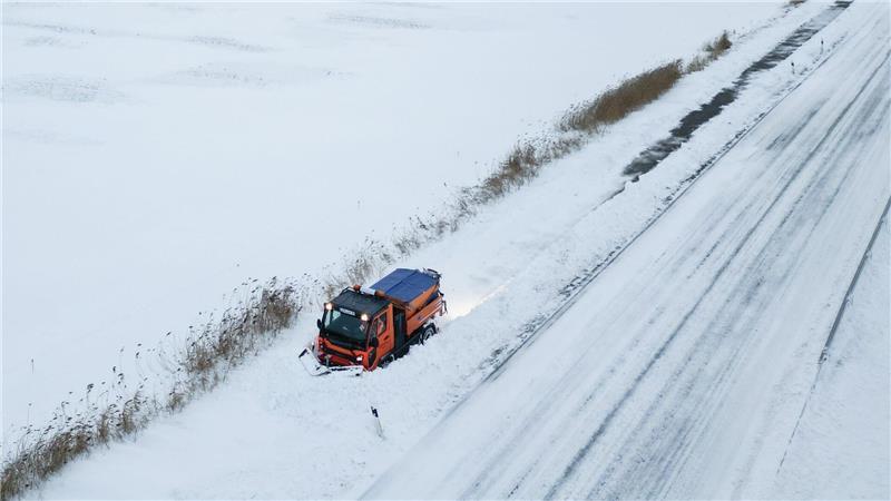 Schneepflug kämpft gegen Verwehungen auf Gehweg bei Bingum