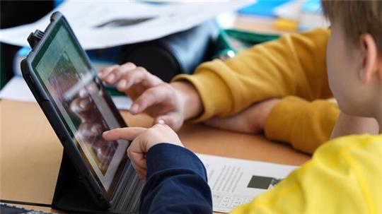 Schüler arbeiten gemeinsam an einem Tablet (Symbolbild).