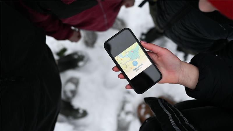 Schüler blicken auf ein Smartphone, das den Schulausfall für den Landkreis Leer anzeigt.