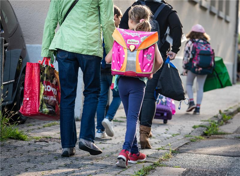 Schüler und Eltern sind zu Fuß unterwegs zu einer Grundschule. Foto: Frank Rumpenhorst/dpa