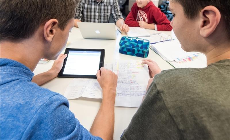 Schüler und ein Lehrer sitzen an einer Gesamtschule vor ihren Tablets und einem Laptop. Foto: picture alliance / Patrick Seeger/dpa