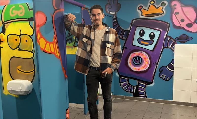 Schülervertreter Raphael Grundmann zeigt die mit Urban Art gestaltete Männertoilette an der IGS Buxtehude.